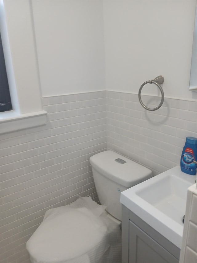 bathroom featuring vanity, tile walls, and toilet