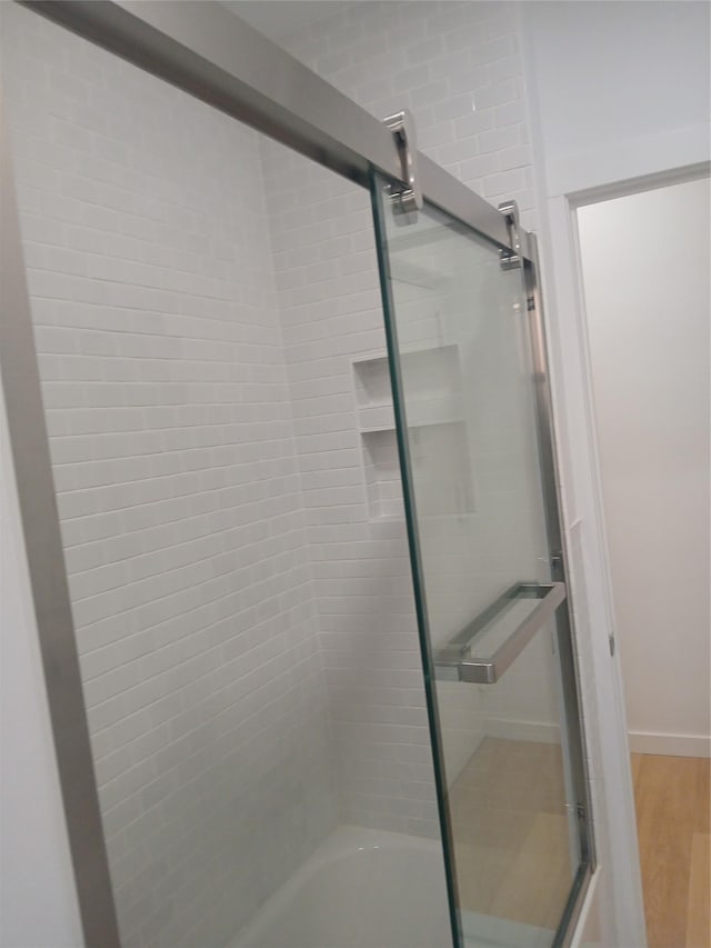 bathroom featuring wood-type flooring and combined bath / shower with glass door