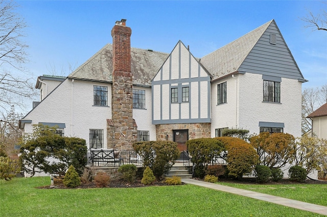 view of front of house with stone siding, a front lawn, a chimney, and stucco siding