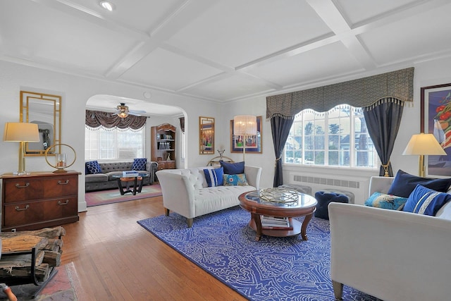 living area with arched walkways, hardwood / wood-style floors, coffered ceiling, and radiator