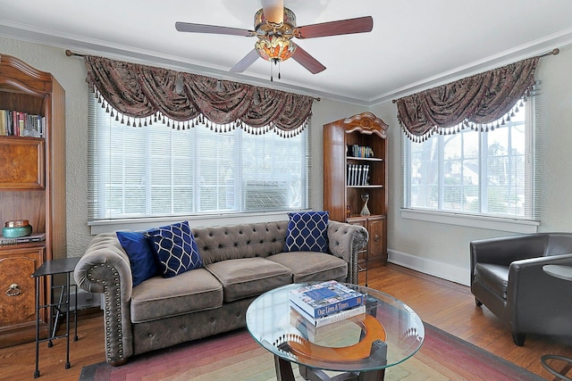 living room with ornamental molding, ceiling fan, baseboards, and wood finished floors