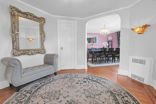 living area with arched walkways, radiator heating unit, wood finished floors, and a notable chandelier