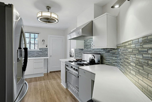 kitchen with light countertops, appliances with stainless steel finishes, light wood-style floors, white cabinetry, and exhaust hood