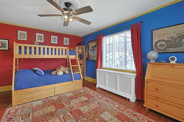 bedroom featuring baseboards, a ceiling fan, radiator heating unit, wood finished floors, and a textured ceiling