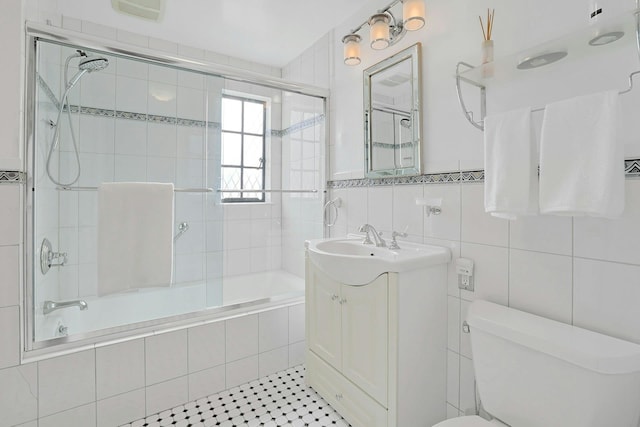 bathroom featuring toilet, tiled shower / bath combo, visible vents, vanity, and tile walls