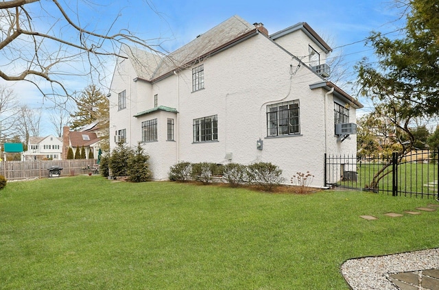 view of home's exterior with stucco siding, a chimney, fence, and a yard