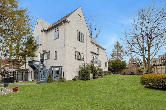 view of side of home with stairway, fence, and a lawn