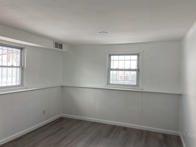 unfurnished room featuring dark wood-type flooring and plenty of natural light