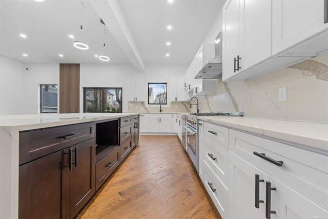 kitchen with wall chimney range hood, light hardwood / wood-style flooring, light stone counters, stainless steel range, and white cabinets