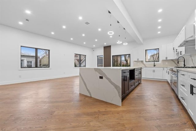 kitchen featuring high end stainless steel range, light stone countertops, white cabinets, and a kitchen island