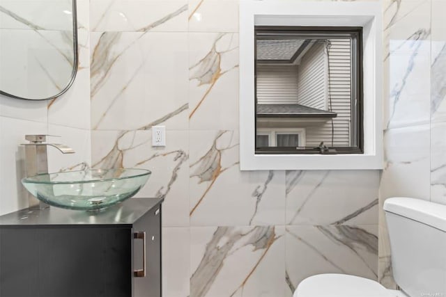 bathroom with vanity, tile walls, and toilet