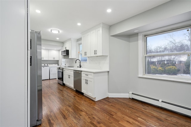 kitchen with a baseboard radiator, stainless steel appliances, independent washer and dryer, and white cabinets