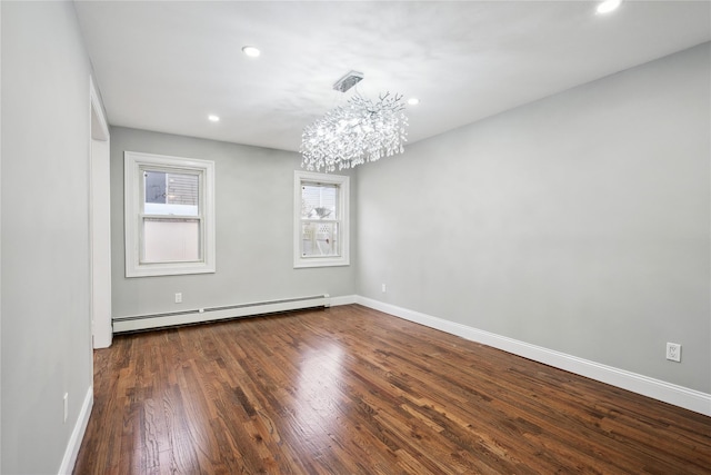 spare room with a baseboard radiator, dark hardwood / wood-style floors, and a chandelier