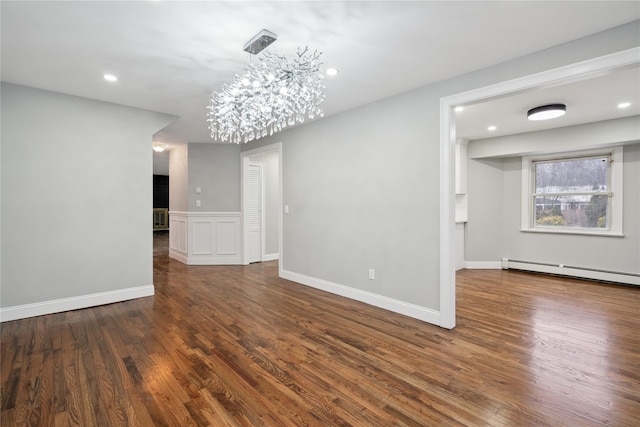 unfurnished room with dark hardwood / wood-style flooring, a chandelier, and a baseboard heating unit