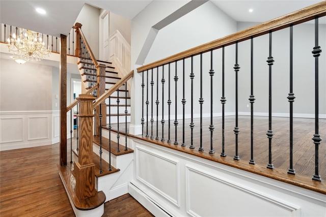 staircase with wood-type flooring and an inviting chandelier