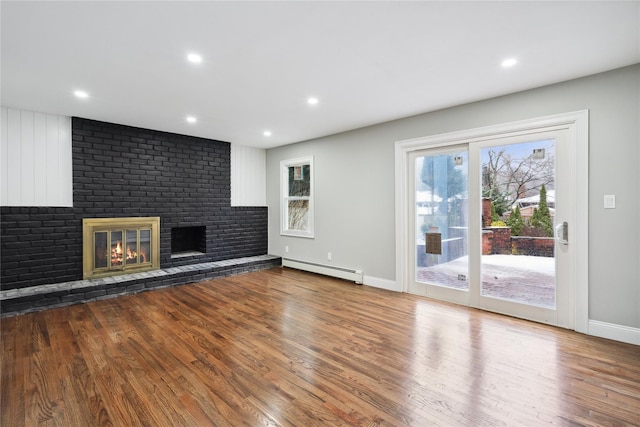 unfurnished living room with a brick fireplace, hardwood / wood-style flooring, and baseboard heating