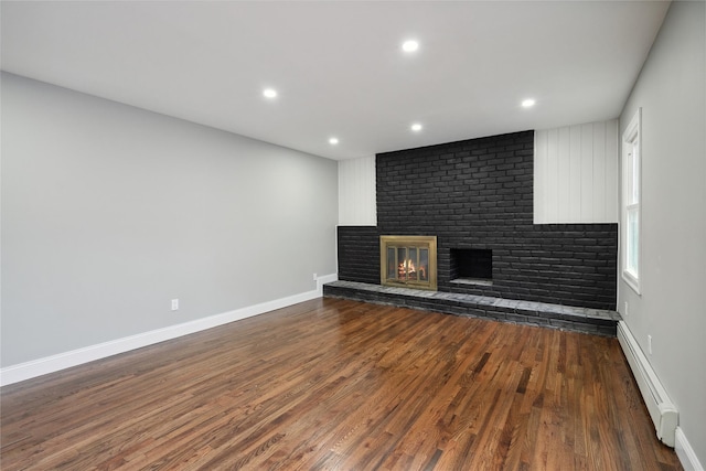 unfurnished living room featuring a fireplace, dark hardwood / wood-style floors, and baseboard heating