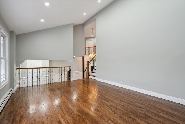 empty room with a baseboard radiator, vaulted ceiling, and hardwood / wood-style floors