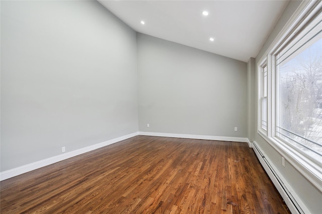 spare room featuring vaulted ceiling, dark hardwood / wood-style floors, and baseboard heating