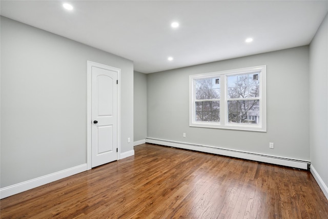 unfurnished room with a baseboard heating unit and hardwood / wood-style floors