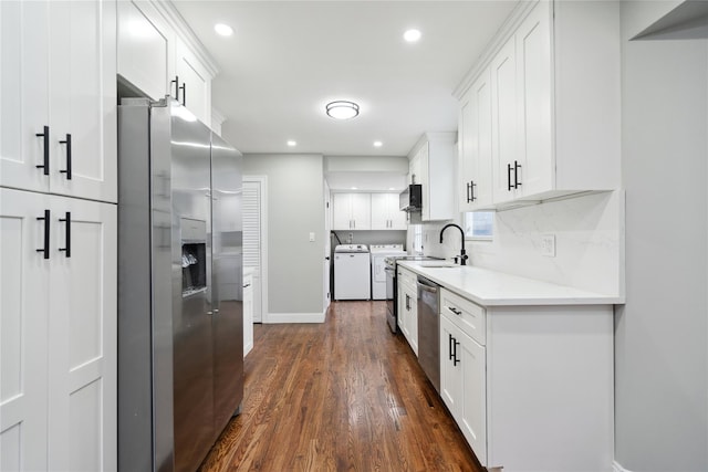 kitchen with dark wood-type flooring, stainless steel appliances, separate washer and dryer, and white cabinets