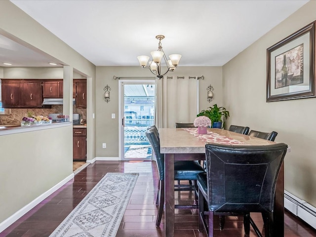 dining room with dark wood-type flooring, a chandelier, and a baseboard heating unit