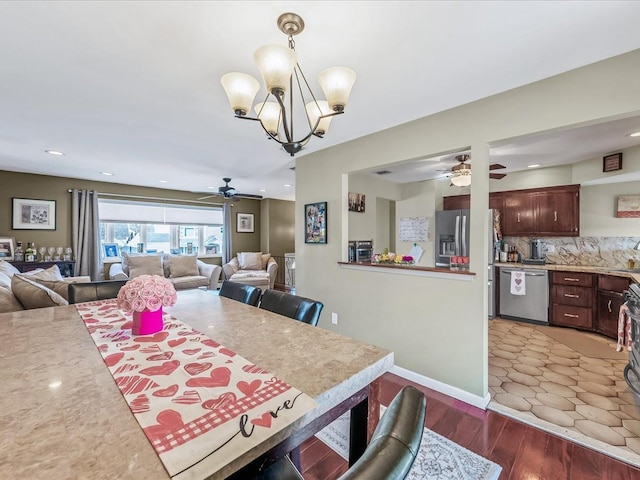 dining room with dark wood-type flooring and ceiling fan with notable chandelier