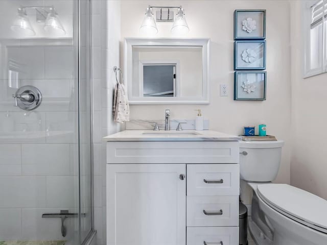 bathroom with a shower with door, vanity, and toilet