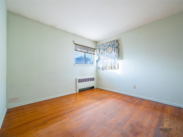 empty room with hardwood / wood-style floors and radiator heating unit