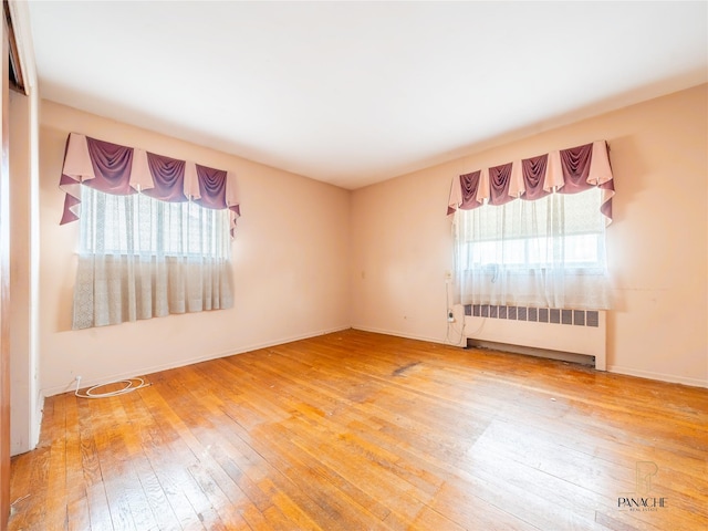 unfurnished room with hardwood / wood-style flooring, a healthy amount of sunlight, and radiator