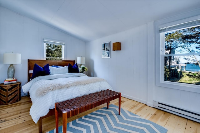 bedroom featuring lofted ceiling, hardwood / wood-style flooring, and a baseboard radiator