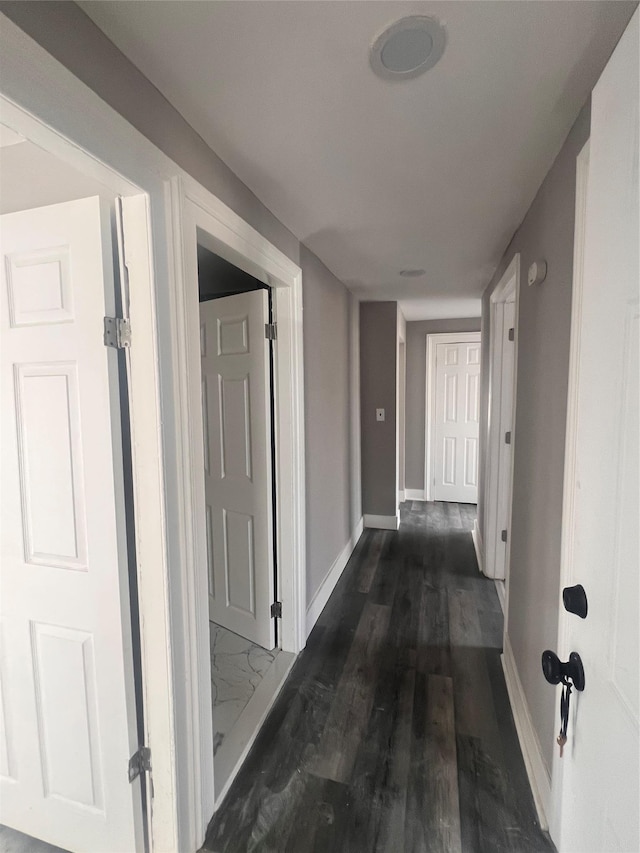 hall with dark wood-type flooring and baseboards