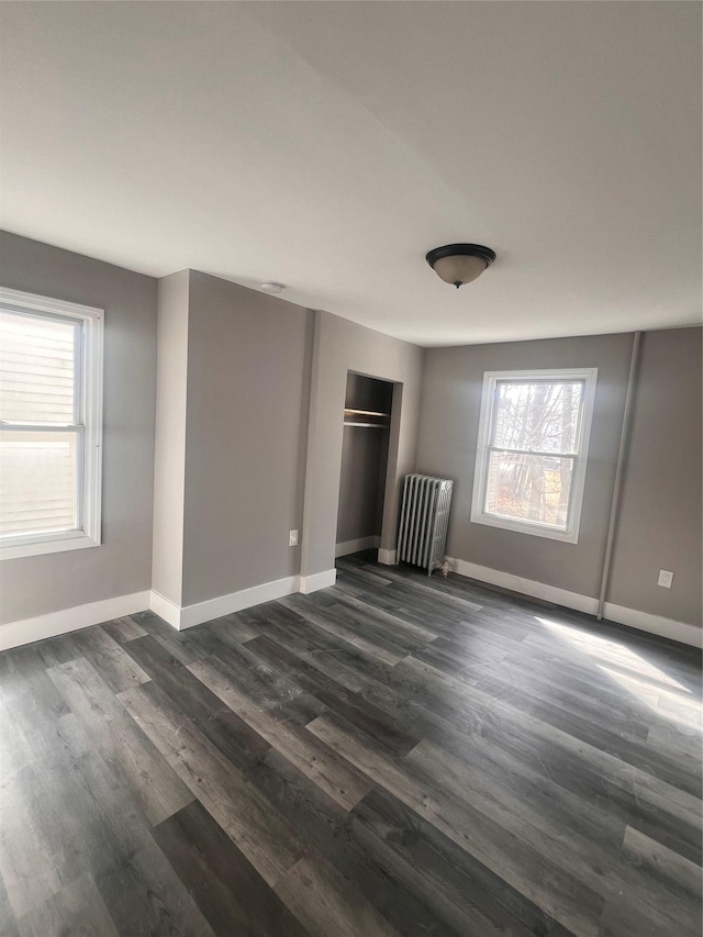 unfurnished bedroom with a closet, baseboards, radiator, and dark wood-style floors