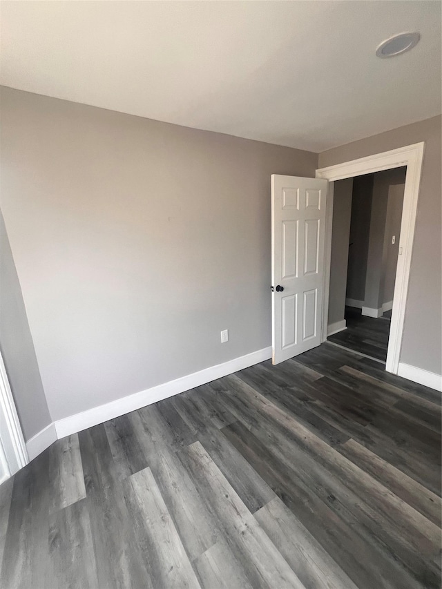 unfurnished room with baseboards and dark wood-type flooring