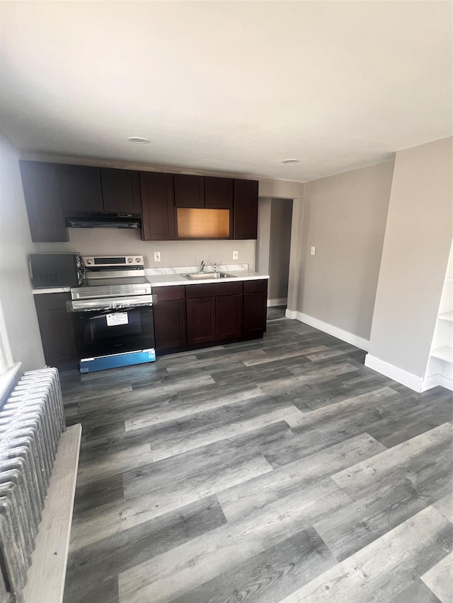 kitchen featuring baseboards, under cabinet range hood, light countertops, stainless steel range with electric cooktop, and dark wood-style floors