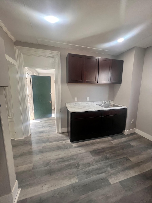 kitchen featuring a sink, baseboards, dark brown cabinets, and wood finished floors