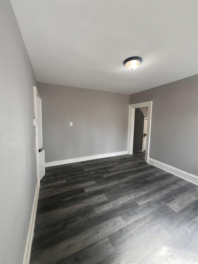 spare room featuring dark wood-style floors and baseboards