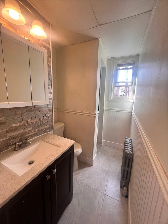 bathroom featuring tile patterned flooring, radiator, toilet, wainscoting, and vanity