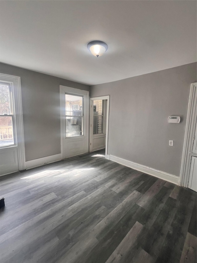 unfurnished room with baseboards and dark wood-style floors