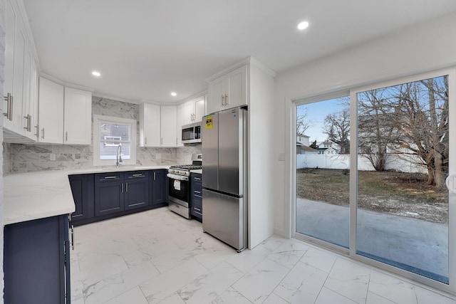 kitchen featuring tasteful backsplash, white cabinetry, sink, stainless steel appliances, and light stone countertops