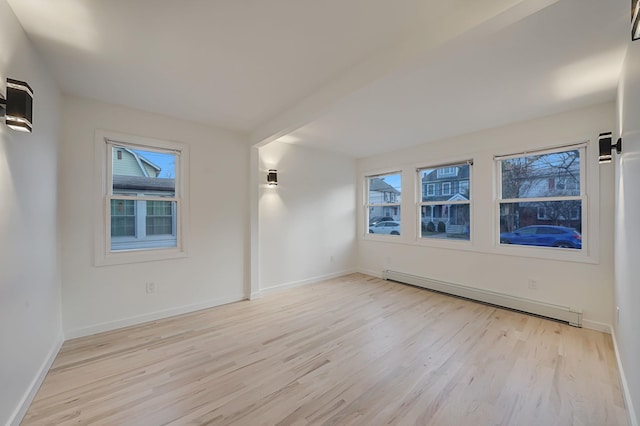 unfurnished room featuring light wood-type flooring and a baseboard heating unit