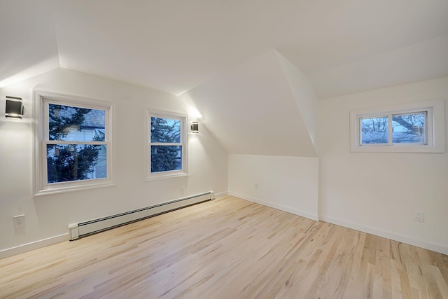 additional living space featuring vaulted ceiling, light wood-type flooring, and baseboard heating