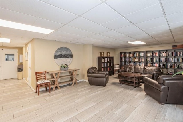 living room with a paneled ceiling and baseboards