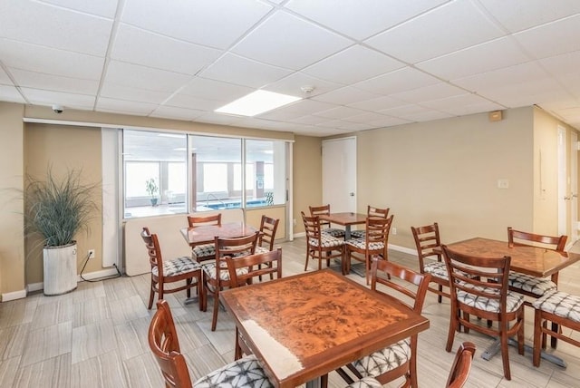 dining space with a paneled ceiling and baseboards