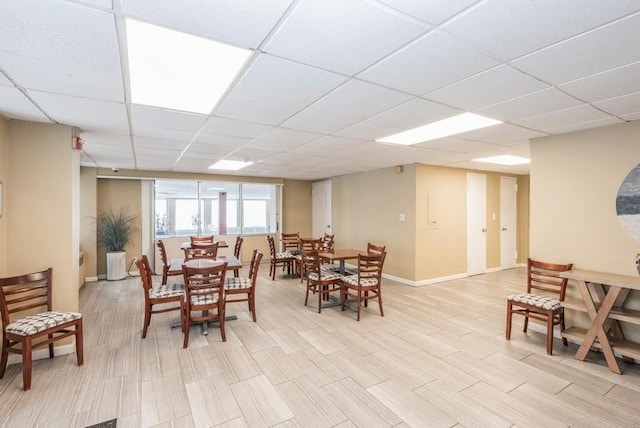 dining space with a drop ceiling and baseboards