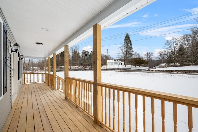 snow covered deck featuring covered porch