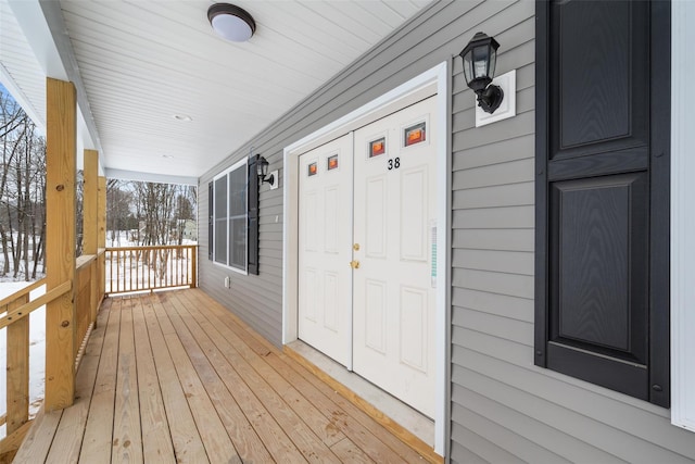 snow covered deck featuring covered porch