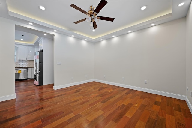 spare room featuring a raised ceiling, ceiling fan, and dark hardwood / wood-style flooring