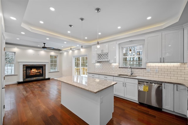 kitchen featuring sink, white cabinetry, a tray ceiling, decorative light fixtures, and stainless steel dishwasher