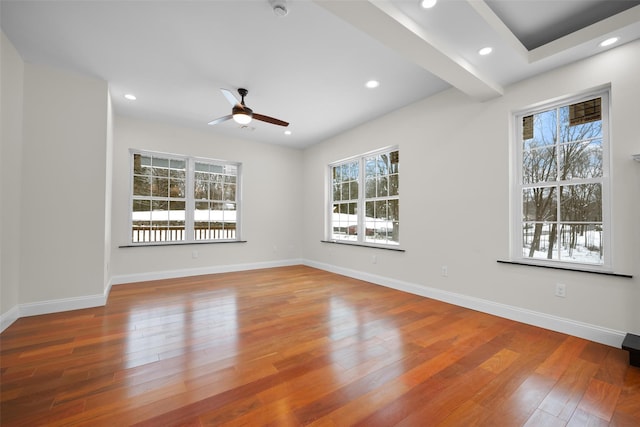 empty room with ceiling fan, plenty of natural light, and hardwood / wood-style floors